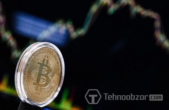 Монета Bitcoin і графік, який показує зміни курсу